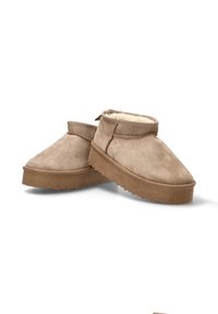 Zapatos de ante marrón claro con puntera redondeada, forro de piel de oveja y un diseño de perfil bajo, con una suela texturizada y detalles de costura mínimos.