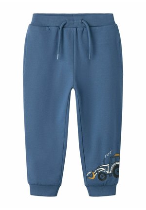 Pantalon de survêtement bleu pour enfants avec taille et poignets élastiques, avec un petit motif de tracteur près de la cheville gauche.