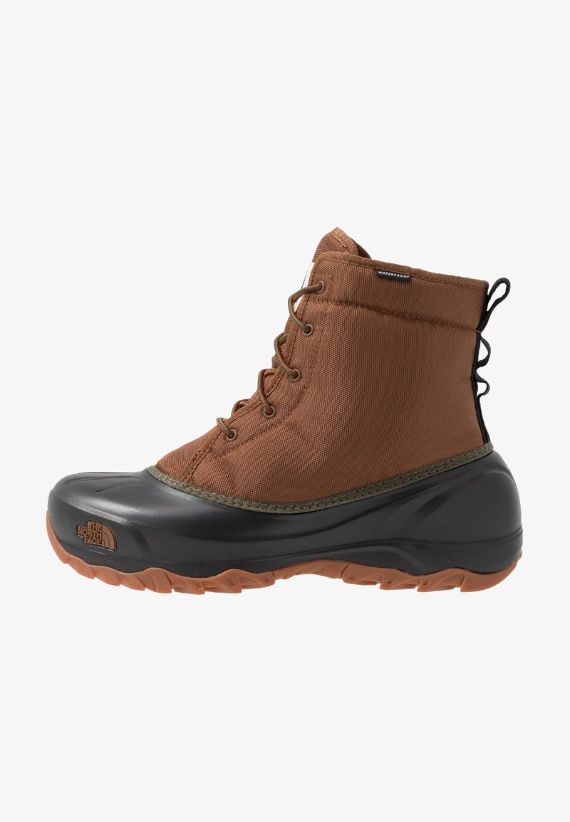 Botte d’hiver marron imperméable à lacets avec partie inférieure en caoutchouc noir, semelle robuste et languette au talon pour une utilisation extérieure.