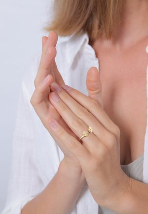 Anello d'oro con accenti a forma di farfalla, design semplice e superficie liscia. Indossato su dita con unghie naturali, mani in posizione rilassata.