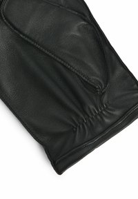 Gant en cuir noir avec un poignet froncé, texture lisse et design courbé, mettant en valeur sa forme élégante et ajustée.