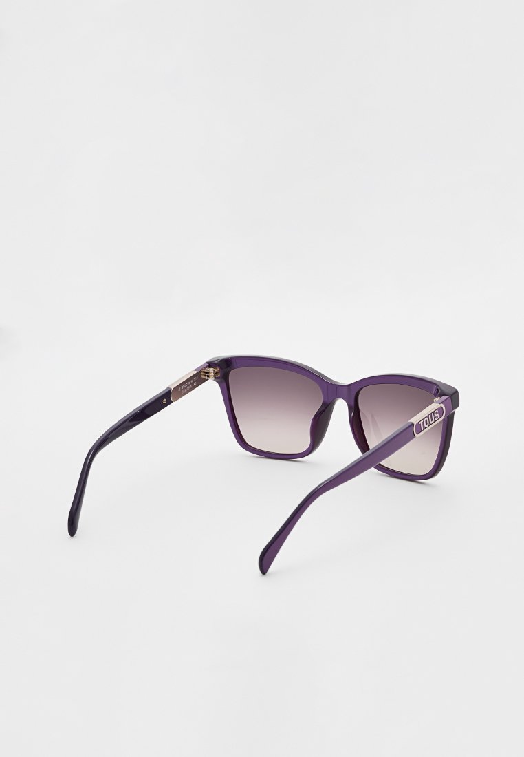 Fioletowe okulary przeciwsłoneczne z elegancką, wyrazistą oprawą. Gradientowe soczewki przechodzą od ciemnego odcienia do jasnego. Po bokach znajduje się logo marki na metalowym akcencie.