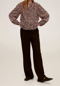 Bloemenprint bloes met wijdvallende mouwen en een geraffineerde taille, gecombineerd met loszittende, donkerbruine broeken en gestructureerde bruine schoenen.