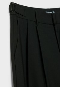 Pantalon noir plissé avec boucle d'ajustement latérale et passants de ceinture, fabriqué en tissu lisse.