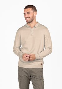 Polo shirt beige a maniche lunghe con colletto, tre bottoni e polsini a costine. Presenta una piccola patch del logo marrone sul lato.