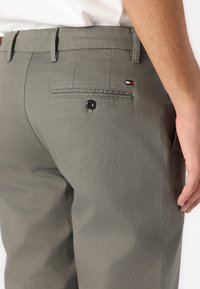 Graue Baumwolltwill-Hosen mit einer Gesäßtasche, Ein-Knopf-Verschluss und einem kleinen tricolor Logo-Akzent am Bund.