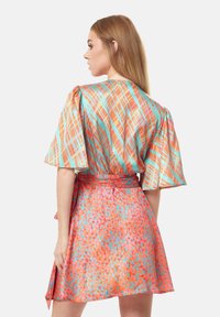 Colorful dress featuring a vibrant orange fabric with blue and pink patterns; short sleeves, belted waist, and flared skirt design.
