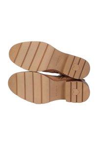 Calzature con suola in gomma marrone, dalla texture liscia e con battistrada decorato, caratterizzato da scanalature orizzontali e un dettaglio a forma di cuore sulla suola.