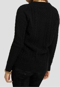 Pull noir en maille torsadée mettant en avant des motifs texturés, un col rond et des bords-côtes aux poignets et à l'ourlet. Il présente une coupe décontractée et un matériau doux.