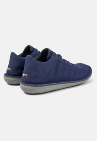 Navy blue fabric sneakers with a textured surface, gray sole, and black interior. Features lace-up design and a subtle logo on the heel.