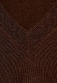 Gros plan d’un tissu tricoté marron avec col en V côtelé montrant la texture et les coutures détaillées.