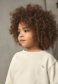 Helebeežide toonis pikkade varrukatega pusa ümarate kaelusega, mille rinnal on väike roheline dinosauruse tikand. Pehme tekstuur, mida kannab laps lokkis juustega.