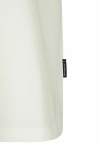 Lichtbeige T-shirt van zacht materiaal, met een rechte snit en een klein marineblauwe etiket aan de ondernaad met witte tekst.