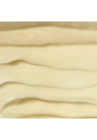 Cremige, glatte und blassfarbige Substanz mit sanften Wellen, die Licht reflektieren und eine glänzende Textur erzeugen. Dezenter Glanz über die gesamte Oberfläche.