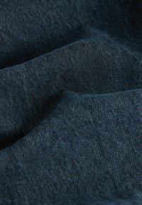 Tume indigo denimkangas pehmea, tekstuurse pinnaga. Materjal on värvigammaga kergeid varieerumisi ja klassikaline twilli kootud muster.