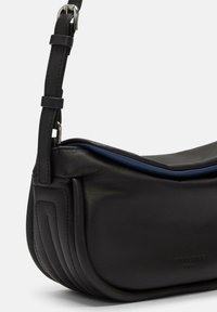 Czarna skórzana torba na ramię o gładkiej fakturze, zakrzywionym kształcie, kontrastowym niebieskim wnętrzu i starannym przeszyciu wzdłuż boków.