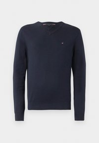 Mornarsko plavi v-neck pulover napravljen od mekane tkanine s dugim rukavima. Ima mali logo na grudima i rebraste manžete i donji rub.