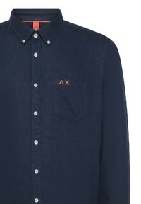 Camicia di cotone blu navy con colletto a bottoni, maniche lunghe, tasca frontale e ricamo geometrico color corallo sulla tasca.