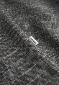 Hallhalli kangas, millel on peened must-valged mustrid, kus servas on nähtav väike silt "GABBA".