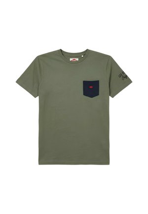 T-shirt manches courtes vert olive avec une poche poitrine bleu marine ornée d'un petit logo diamant rouge et un texte noir sur la manche gauche.