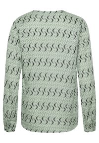 Vaaleanvihreä pitkähihainen paita, jossa on musta kiemurteleva toistuva kuvio, pyöristetty helma ja joustavat hihansuut.