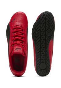 Sneakers rossi in pelle con accenti neri, dotati di una suola in gomma testurizzata, lacci piatti e un colletto imbottito per il comfort.