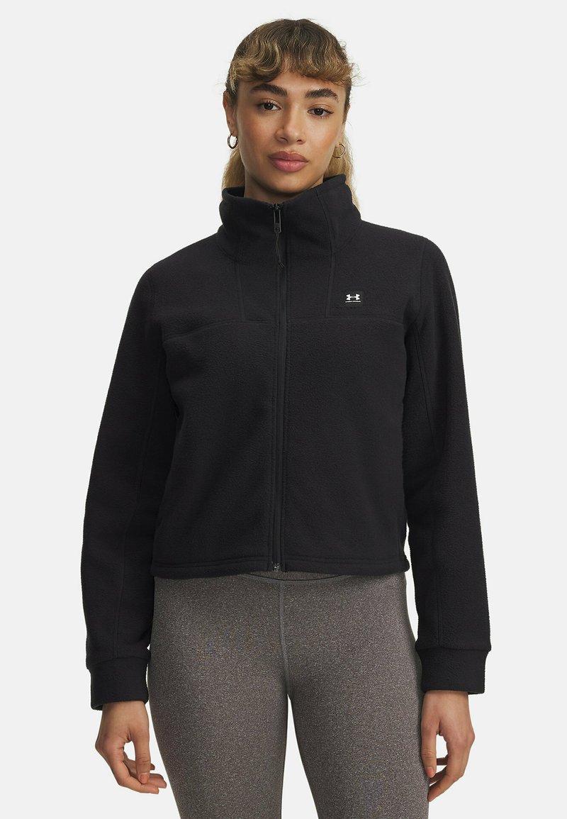 Giacca in pile nera con colletto alto, chiusura con zip e logo sul petto. Presenta maniche lunghe e un design corto. Tessuto strutturato.