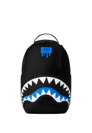 Zaino nero con design di bocca di squalo blu e bianco sulla parte anteriore e una piccola toppa blu vicino alla sommità con testo e gocce.