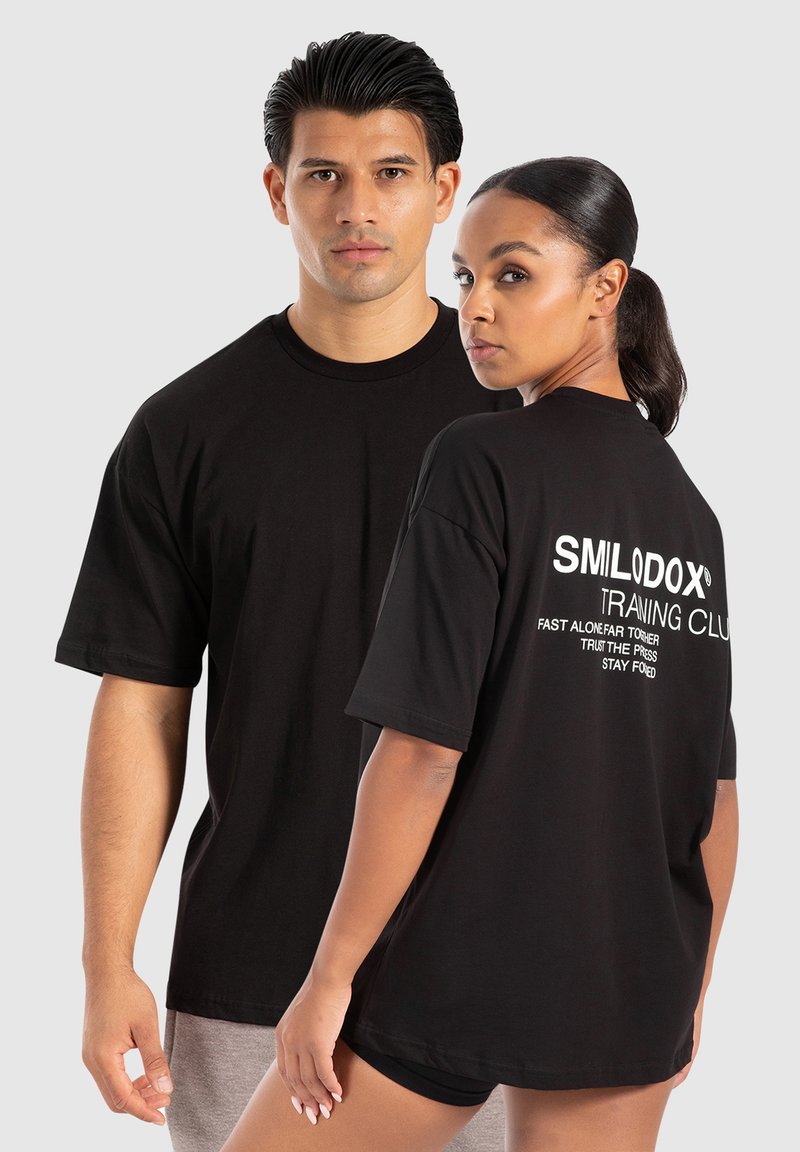 Camisetas de algodón negras de manga corta, con texto blanco en la parte trasera que dice "CLUB DE ENTRENAMIENTO SMILODOX". Corte clásico y escote redondo.