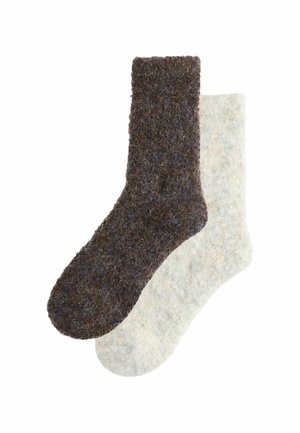Två par strumpor: ett par i mörkbrun med en texturerad finish, och ett par i mjuk ljusbeige med ett subtilt melerat mönster.