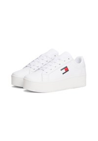 Bílé sportovní sneakers s hladkým syntetickým svrškem, šněrováním, polstrovaným jazykem a masivní gumovou podrážkou s texturovaným vzorem.