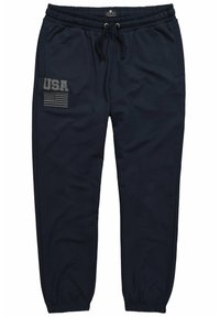 Marineblauwe sweatpants met een elastische tailleband en trekkoord. Heeft een patch aan de linkerkant met "USA" en een grafische afbeelding van de Amerikaanse vlag. Zachte textuur.