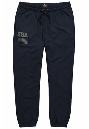 Pantaloni da tuta blu navy con vita elasticizzata e stringa di regolazione. Presenta una toppa sul lato sinistro con la scritta "USA" e un motivo della bandiera americana. Texture morbida.