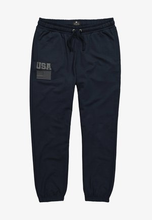 Pantaloni da tuta blu navy con vita elasticizzata e stringa di regolazione. Presenta una toppa sul lato sinistro con la scritta "USA" e un motivo della bandiera americana. Texture morbida.