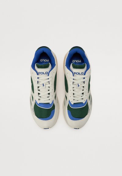 Hvite, grønne og blå sneakers med mesh-overdel, polstret tunge og gummisåle. "Polo"-logoen er tydelig plassert på tungen.
