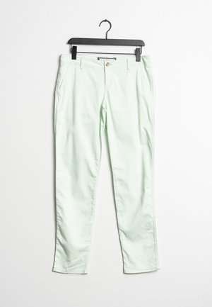 Lys grønne skræddersyede bukser med knaplukning og sidelommer hængende på en sort bøjle mod en hvid baggrund.