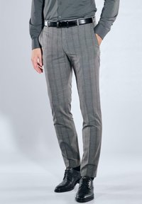 Graue karierte Hose mit schmaler Passform, die eine glatte Textur und Seitentaschen aufweist, kombiniert mit schwarzen Lederschuhen und einem passenden Gürtel.