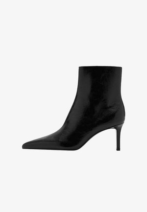 Bota negra hasta el tobillo con diseño de punta, hecha de cuero brillante. Presenta un tacón de aguja y una textura suave. Sin adornos visibles.