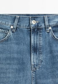 Niebieskie jeansy z denimu z metalowym zapięciem na guzik, szlufkami, przednimi kieszeniami i widocznymi szwami.