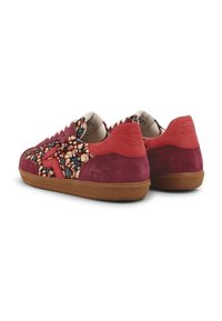 Paire de baskets basses en daim rouge, tissu à motifs floraux et semelles en caoutchouc marron, vues de dos sur fond blanc.