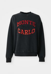 Mustat collegepaita, jossa on pyöreä kaula-aukko ja alhaalle lasketut olkapäät. Vaatteessa on punainen "MONTE CARLO" -teksti ja brändäys, ja se on valmistettu pehmeästä, teksturoidusta kankaasta.