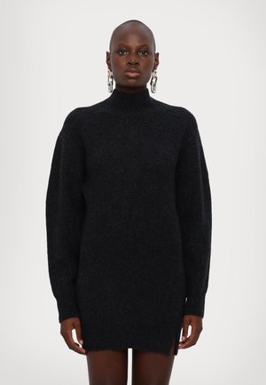 Rochie tricotată neagră, cu model canalat, cu guler înalt, mâneci lungi și slituri laterale la tiv. Fabricată dintr-un material moale, oferind o croială lejeră.