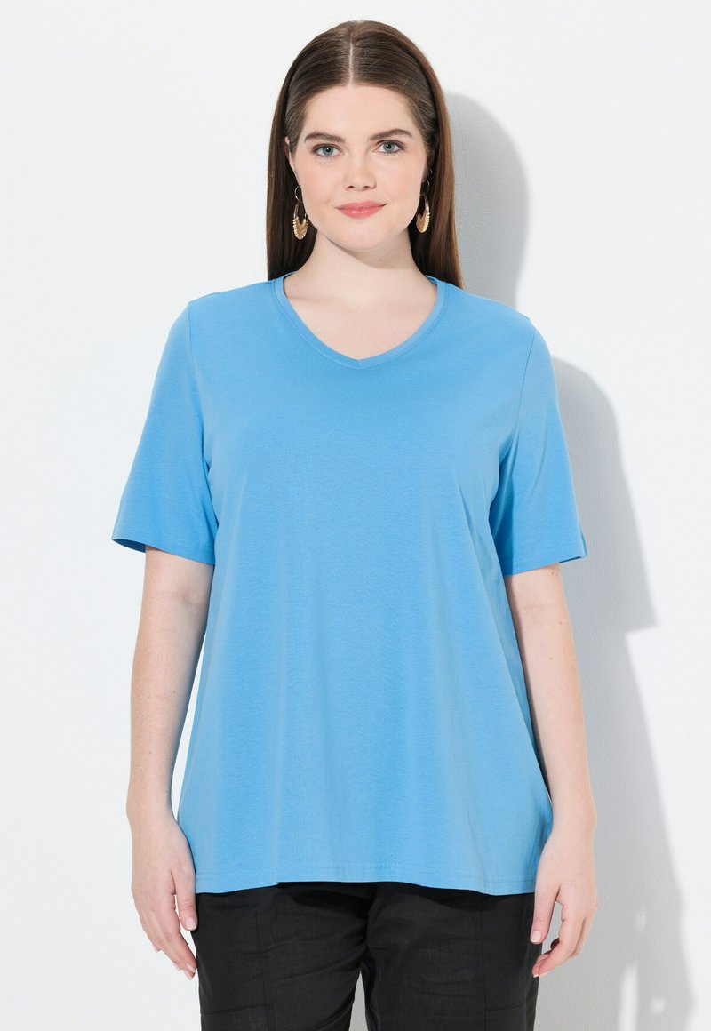 Vaaleansininen, lyhytvartinen V-kaula-aukko t-paita, joka on valmistettu pehmeästä kankaasta ja jossa on väljä istuvuus, yhdistettynä mustiin housuihin, minimalistinen muotoilu.