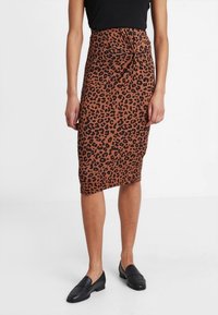 Leopardskinnad midi kjol i brunt med svarta fläckar, åtsittande form, knytdetalj i midjan och textilstruktur. Bärs med svarta loafers.