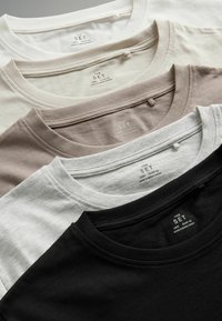 Vier Baumwoll-T-Shirts stapelweise angezeigt: schwarz, hellgrau, beige und cremefarben. Jedes hat einen runden Ausschnitt und Pflegeetiketten.