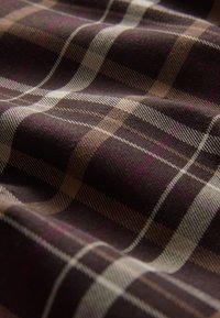 Tissu à carreaux marron avec une texture douce, comprenant des lignes de couleur claire et des accents subtils de rose, présentant un motif à carreaux classique.