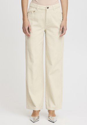 Beige vidbenede bukser med frontlommer og knaplukning, båret med sølvfarvede spidse hæle.