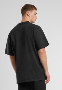 Black oversize t-shirt made from cotton, featuring a round neckline and short sleeves. The back is plain with no visible patterns or logos.