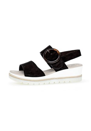 Black suede sandal with a round accent buckle, adjustable strap, open toe, and white wedge sole with textured tread.