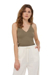 Top in maglia a coste verde oliva con scollo a V, abbinato a pantaloni in lino bianchi a vestibilità ampia con vita elastica e tasche laterali.